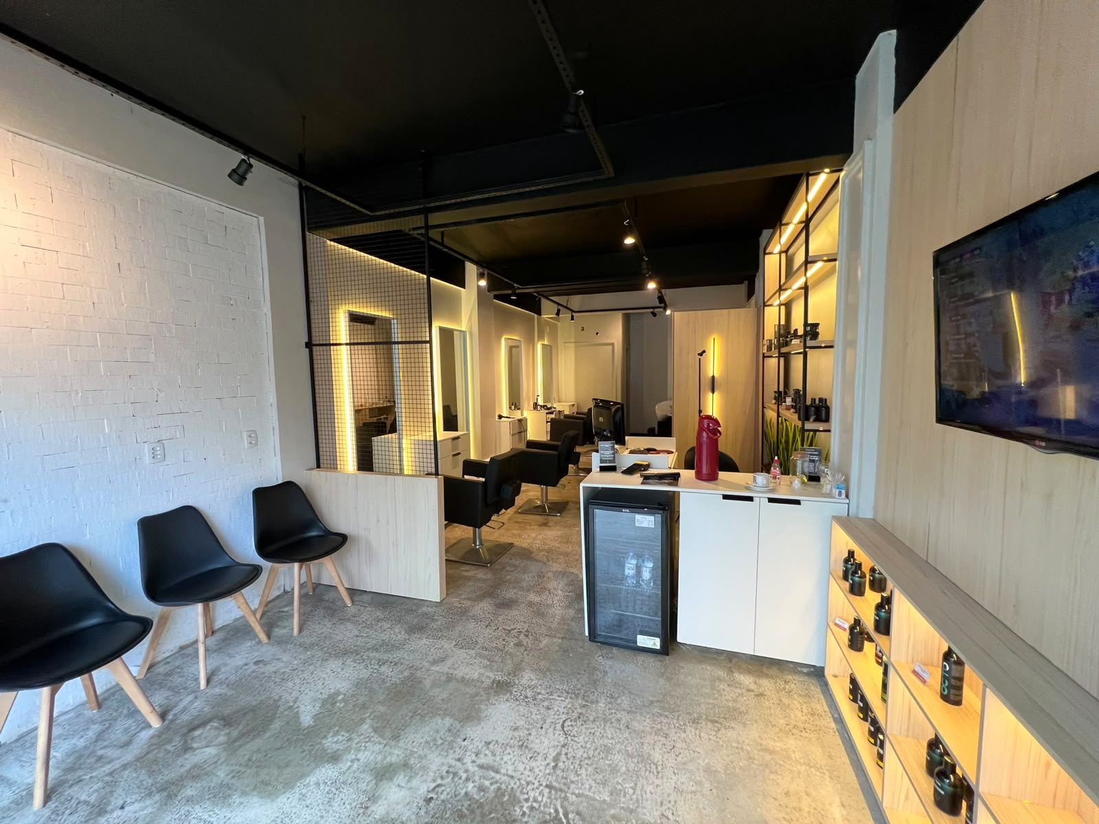 Interior da Barbearia Urban Cut: sala de espera, balcão e as cadeiras com espelhos iluminados